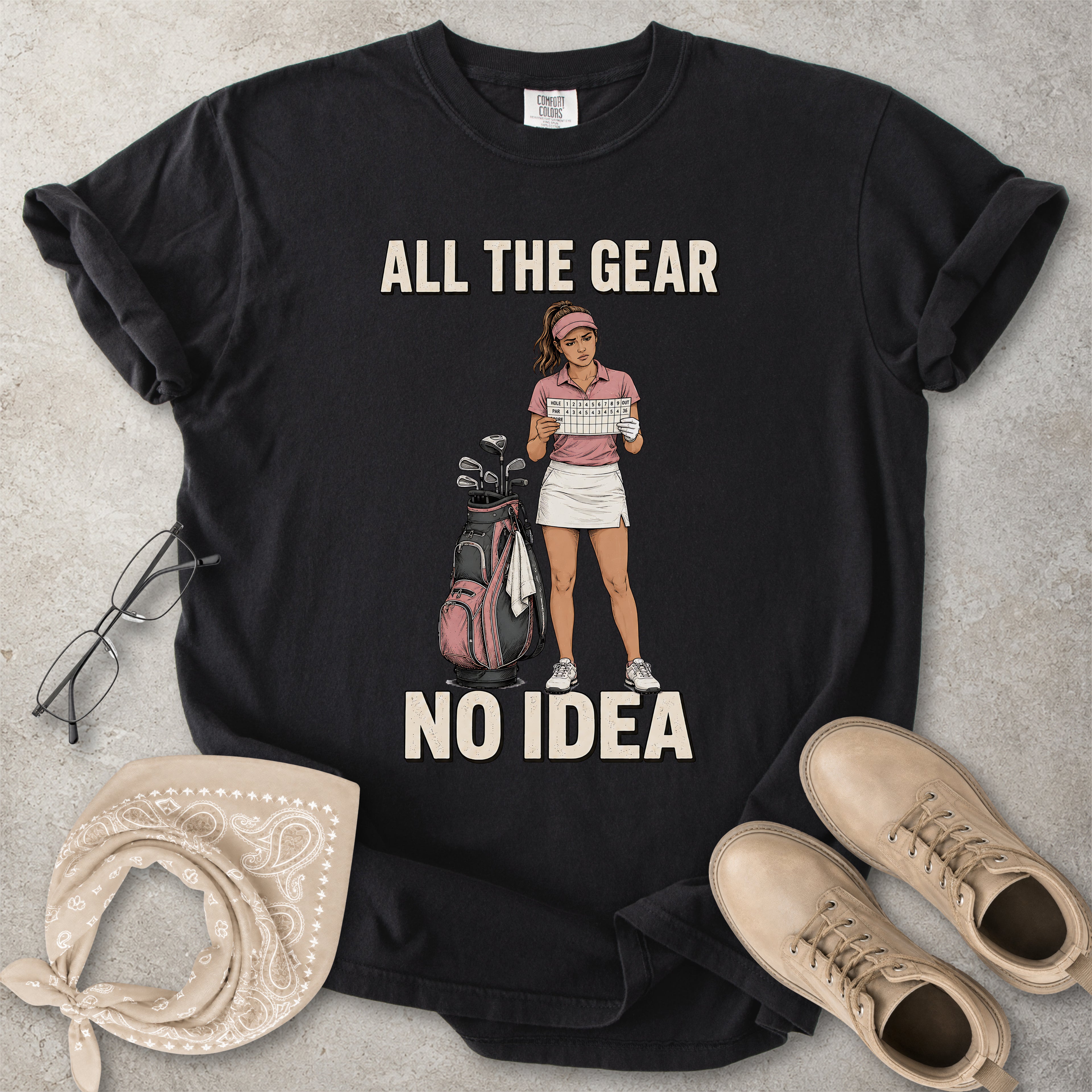 Black Comfort Colors 1717 T-shirt with a funny All the Gear No Idea golf graphic showing a woman golfer holding a scorecard beside a golf bag.