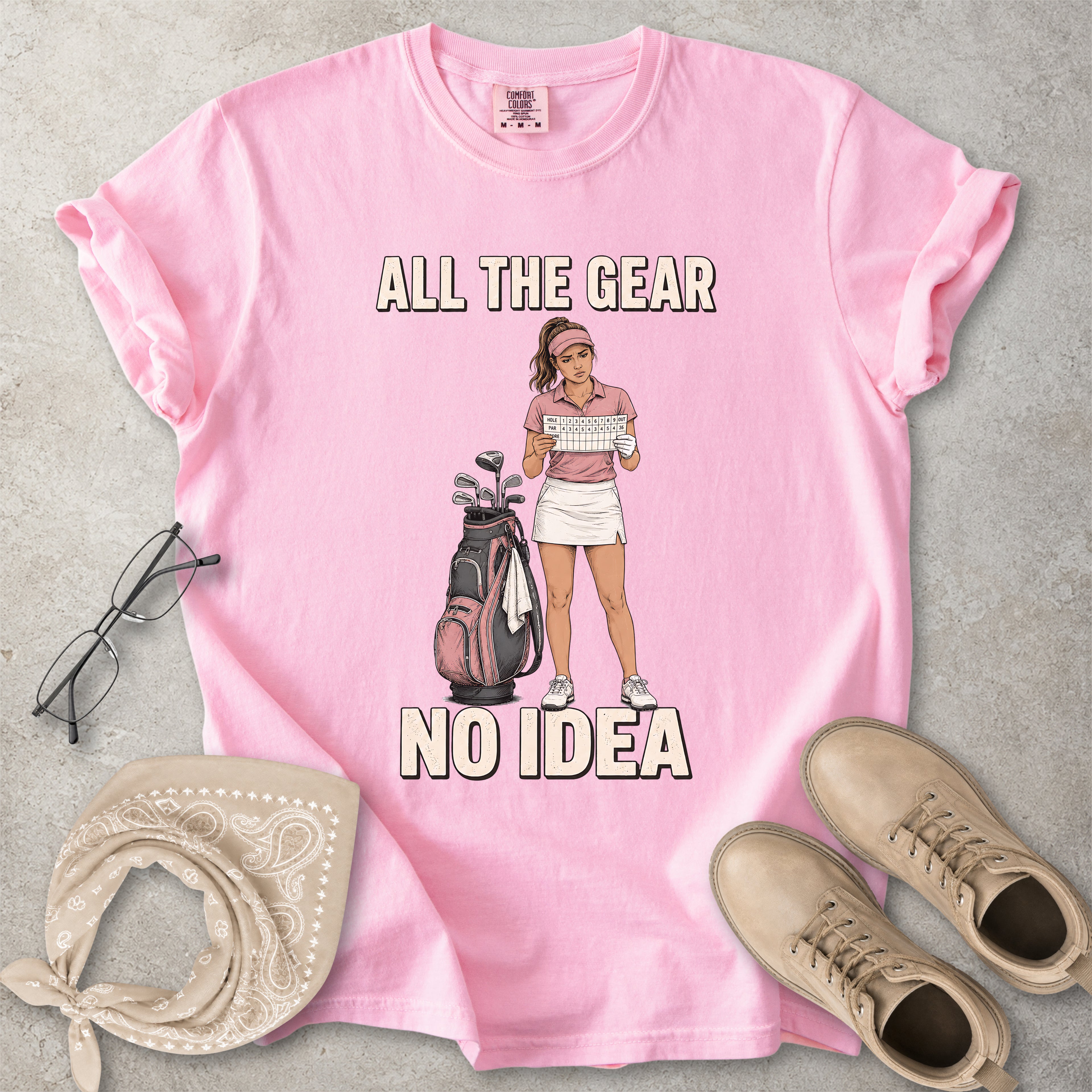 Blossom pink Comfort Colors 1717 T-shirt with a funny All the Gear No Idea golf graphic showing a woman golfer holding a scorecard beside a golf bag.