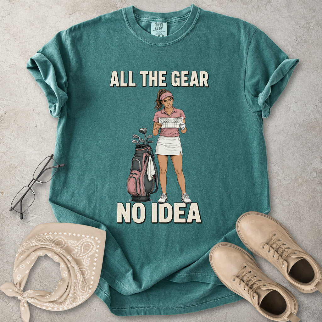Blue spruce Comfort Colors 1717 T-shirt with a funny All the Gear No Idea golf graphic showing a woman golfer holding a scorecard beside a golf bag.
