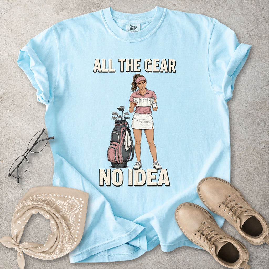 Chambray light blue Comfort Colors 1717 T-shirt with a funny All the Gear No Idea golf graphic showing a woman golfer holding a scorecard beside a golf bag.