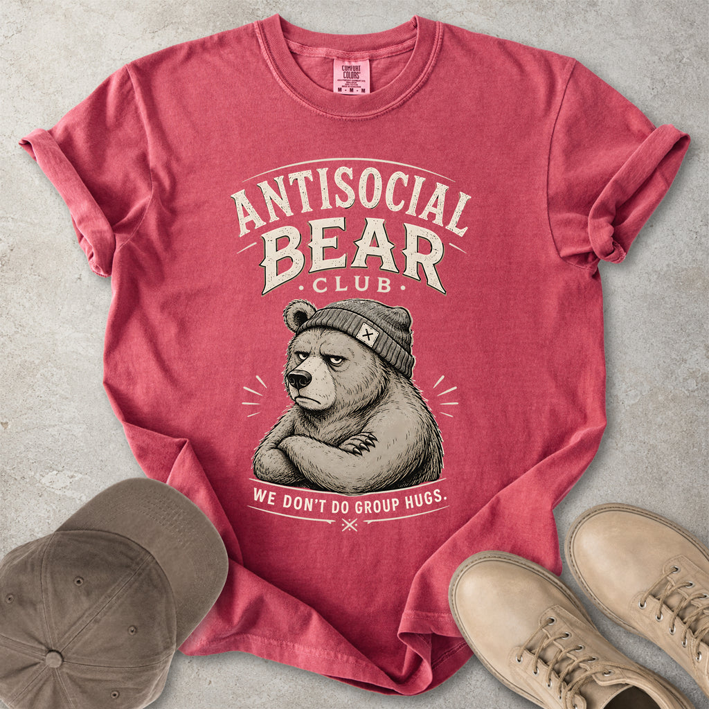 Red t-shirt with 'Antisocial Bear Club' graphic on a gray surface with a cap and shoes.