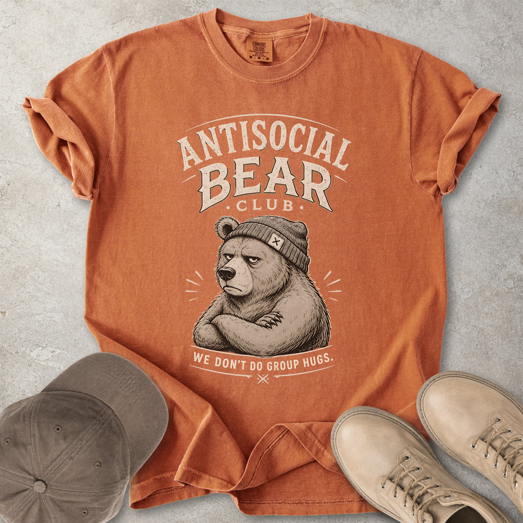 Orange t-shirt with 'Antisocial Bear Club' graphic on a concrete surface with a cap and shoes.