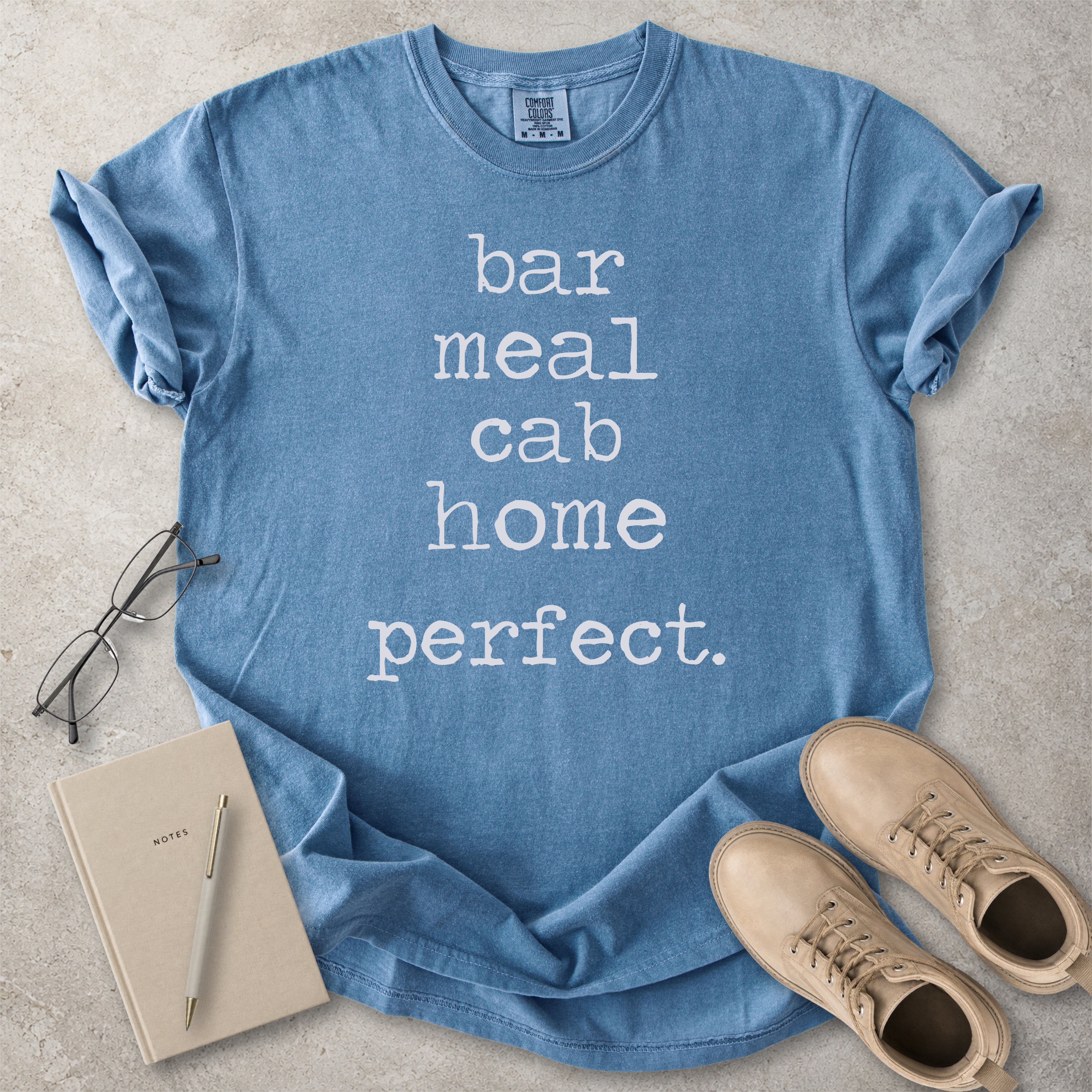 Blue jean Comfort Colors graphic T-shirt with white text reading bar meal cab home perfect, styled with black boots and a black bandana