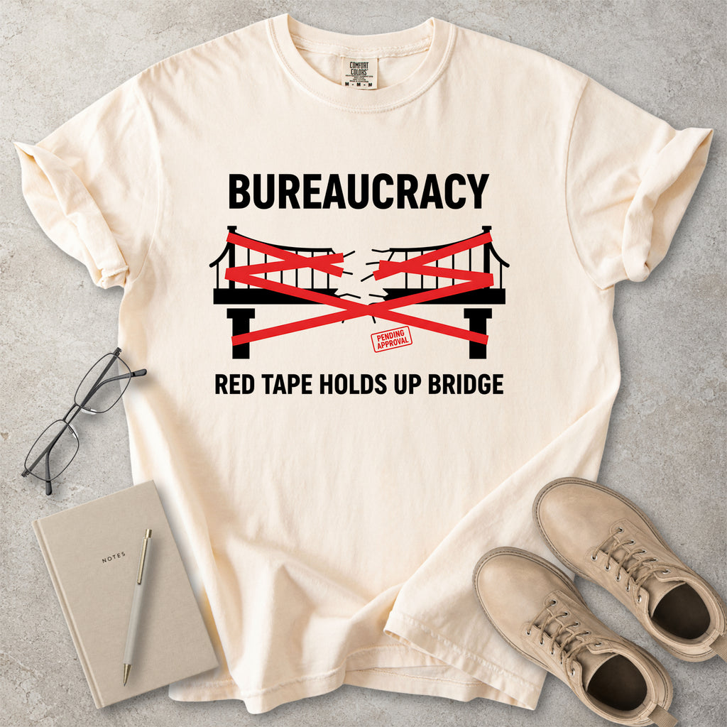 Ivory beige Comfort Colors graphic T-shirt with bureaucracy red tape holds up bridge design, styled with notebook, glasses and tan boots