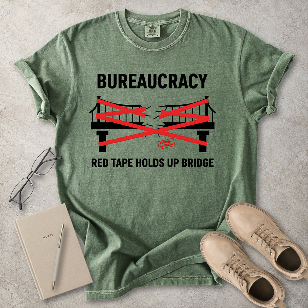 Moss green Comfort Colors graphic T-shirt with bureaucracy red tape holds up bridge design, styled with notebook, glasses and tan boots