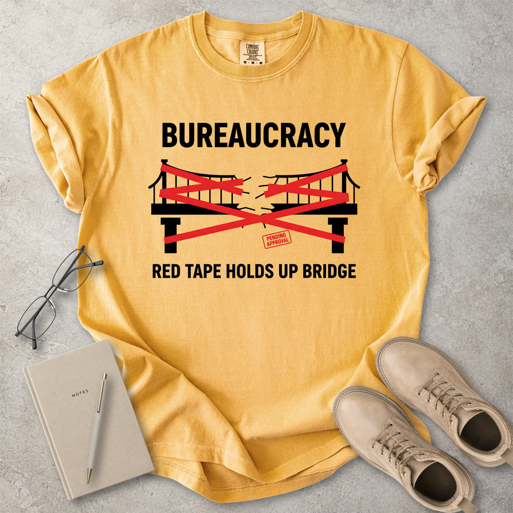 Mustard yellow Comfort Colors graphic T-shirt with bureaucracy red tape holds up bridge design, styled with notebook, glasses and tan boots