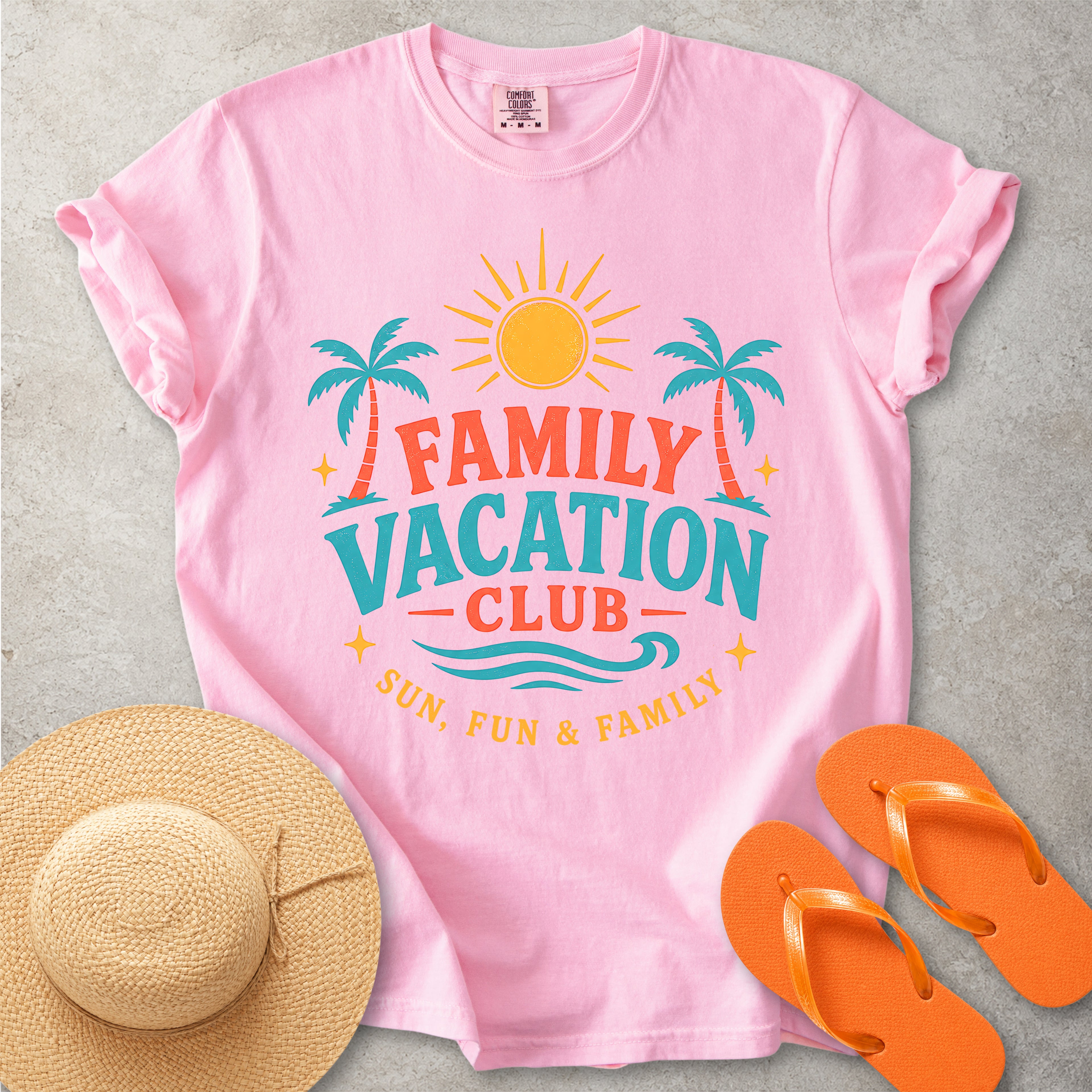 Pink t-shirt with 'Family Vacation Club' design, straw hat, and orange flip-flops on a gray background