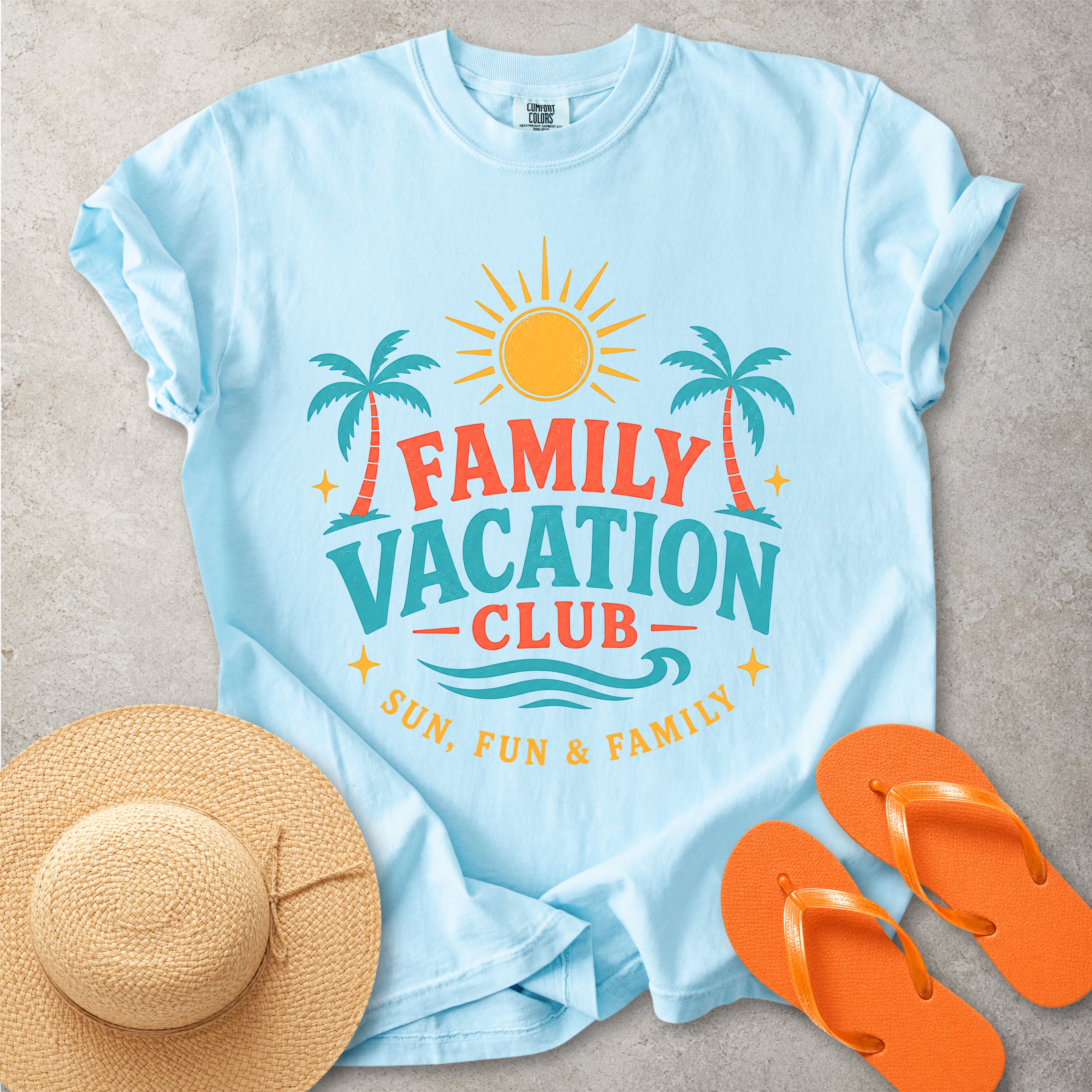 Light blue t-shirt with 'Family Vacation Club' design, straw hat, and orange flip-flops on a gray surface