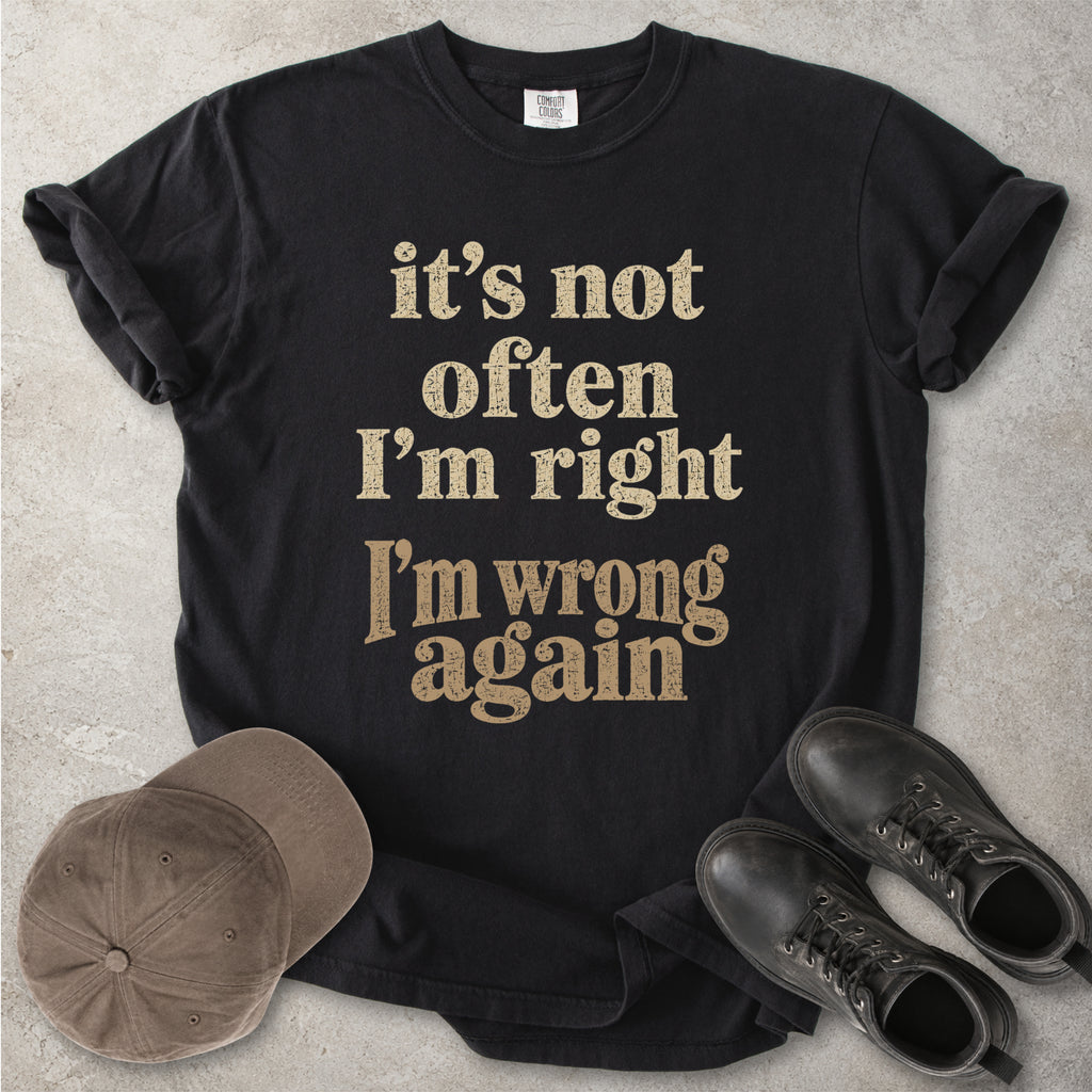 Black Comfort Colors graphic T-shirt with beige text reading it’s not often I’m right I’m wrong again, styled with a cap and black boots