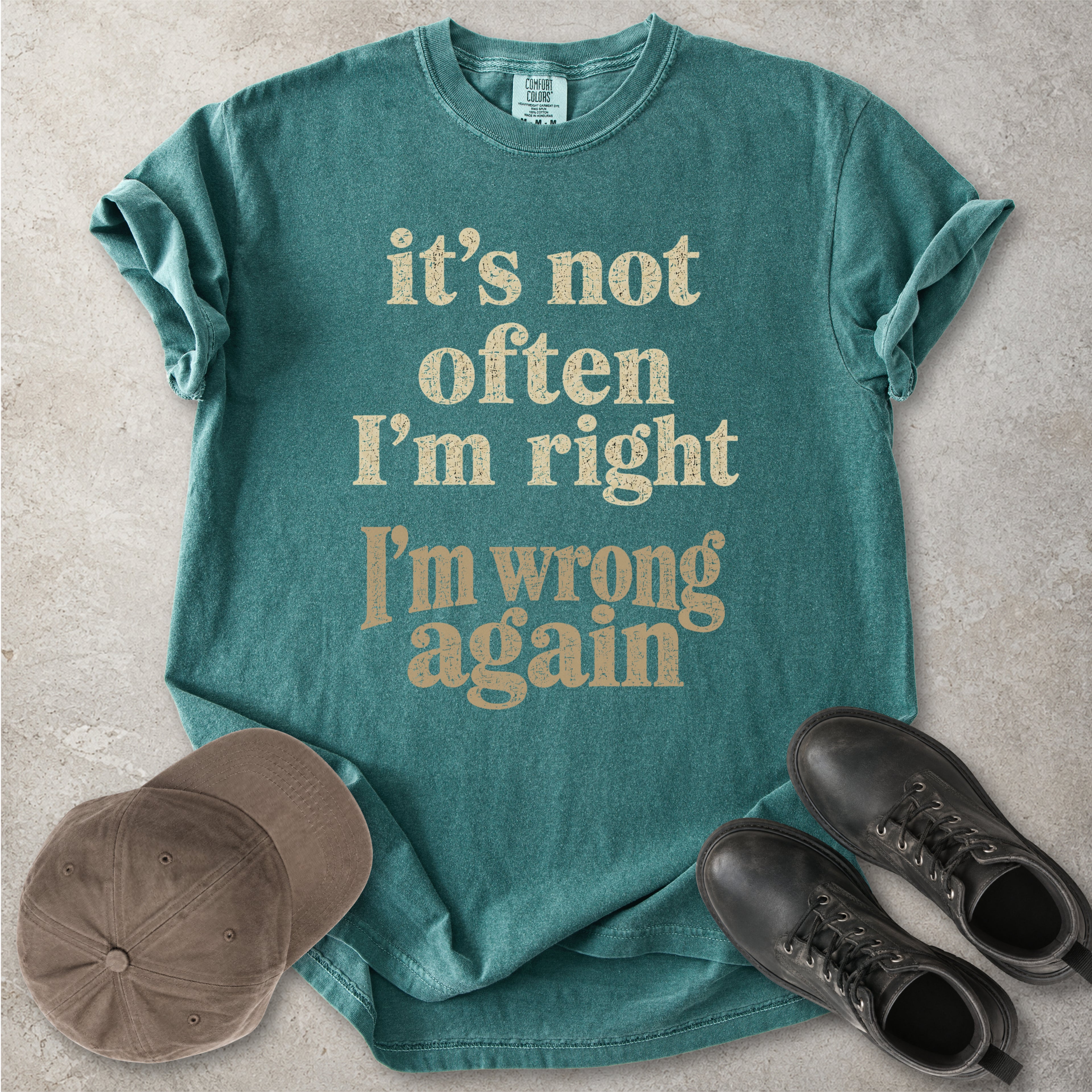 Blue spruce Comfort Colors graphic T-shirt with beige text reading it’s not often I’m right I’m wrong again, styled with a cap and black boots