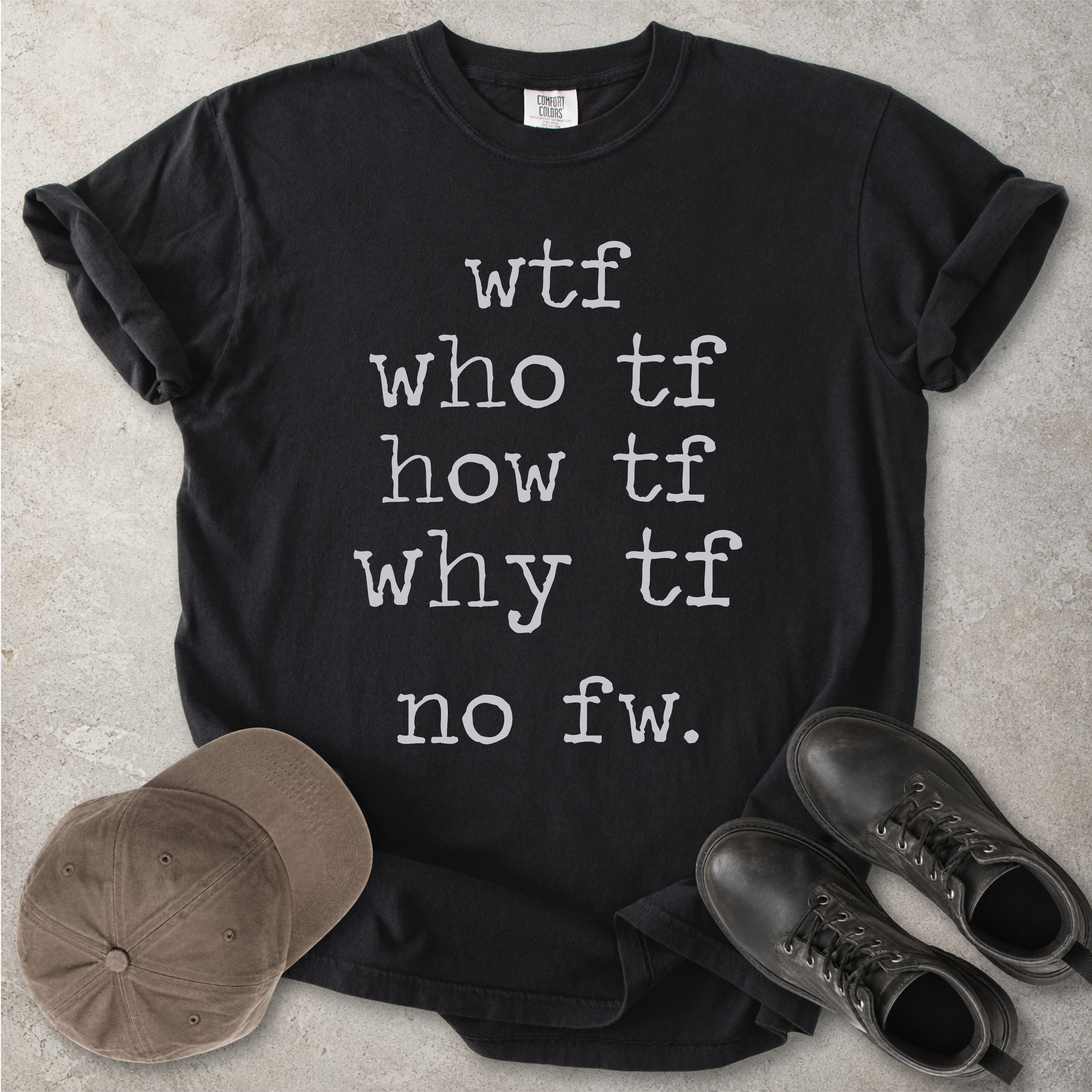 Black Comfort Colors graphic T-shirt with grey text reading wtf, who tf, how tf, why tf and no fw, styled with a brown cap and black boots