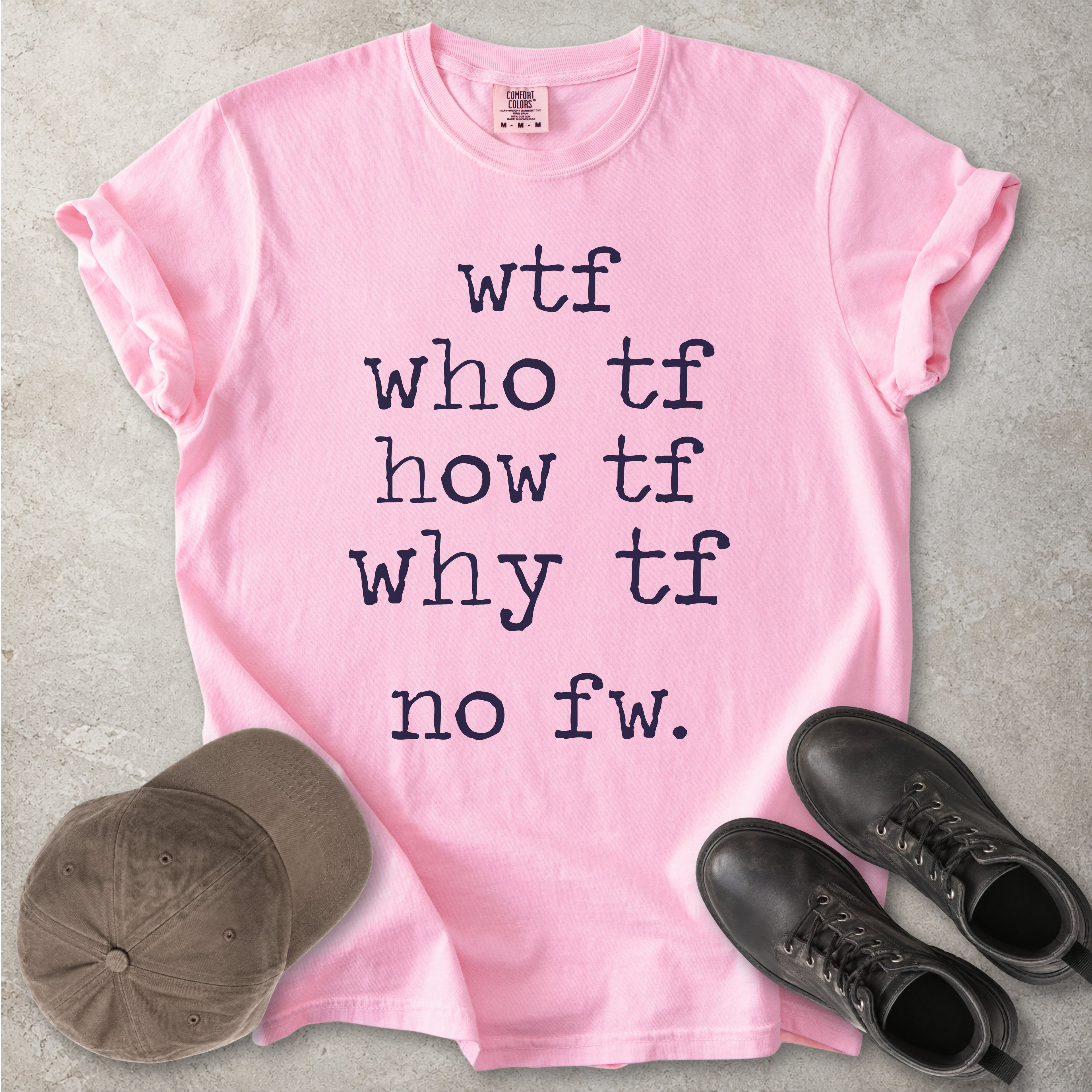 Pink Comfort Colors graphic T-shirt with grey text reading wtf, who tf, how tf, why tf and no fw, styled with a brown cap and black boots