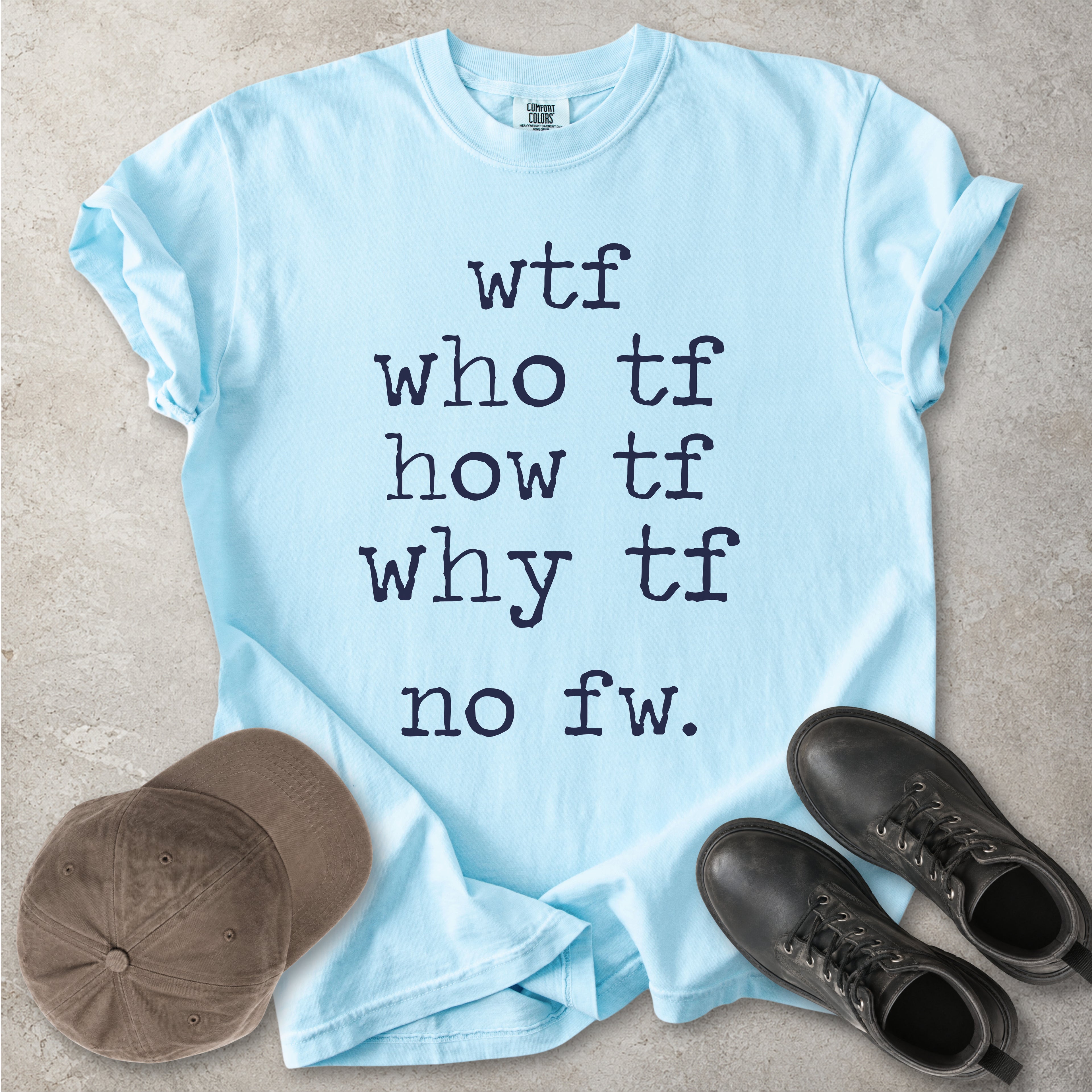 Light blue Comfort Colors graphic T-shirt with grey text reading wtf, who tf, how tf, why tf and no fw, styled with a brown cap and black boots