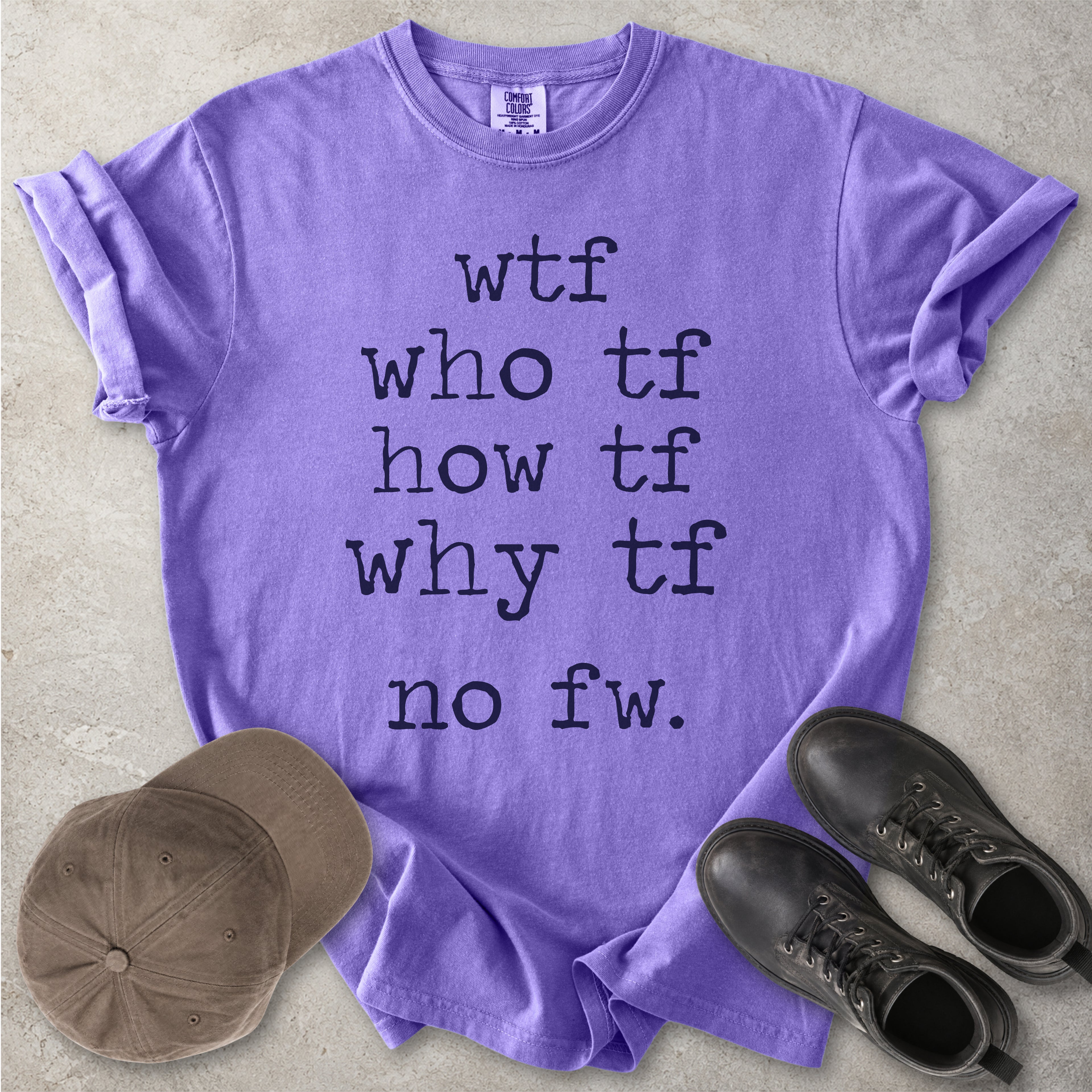 Purple Comfort Colors graphic T-shirt with grey text reading wtf, who tf, how tf, why tf and no fw, styled with a brown cap and black boots