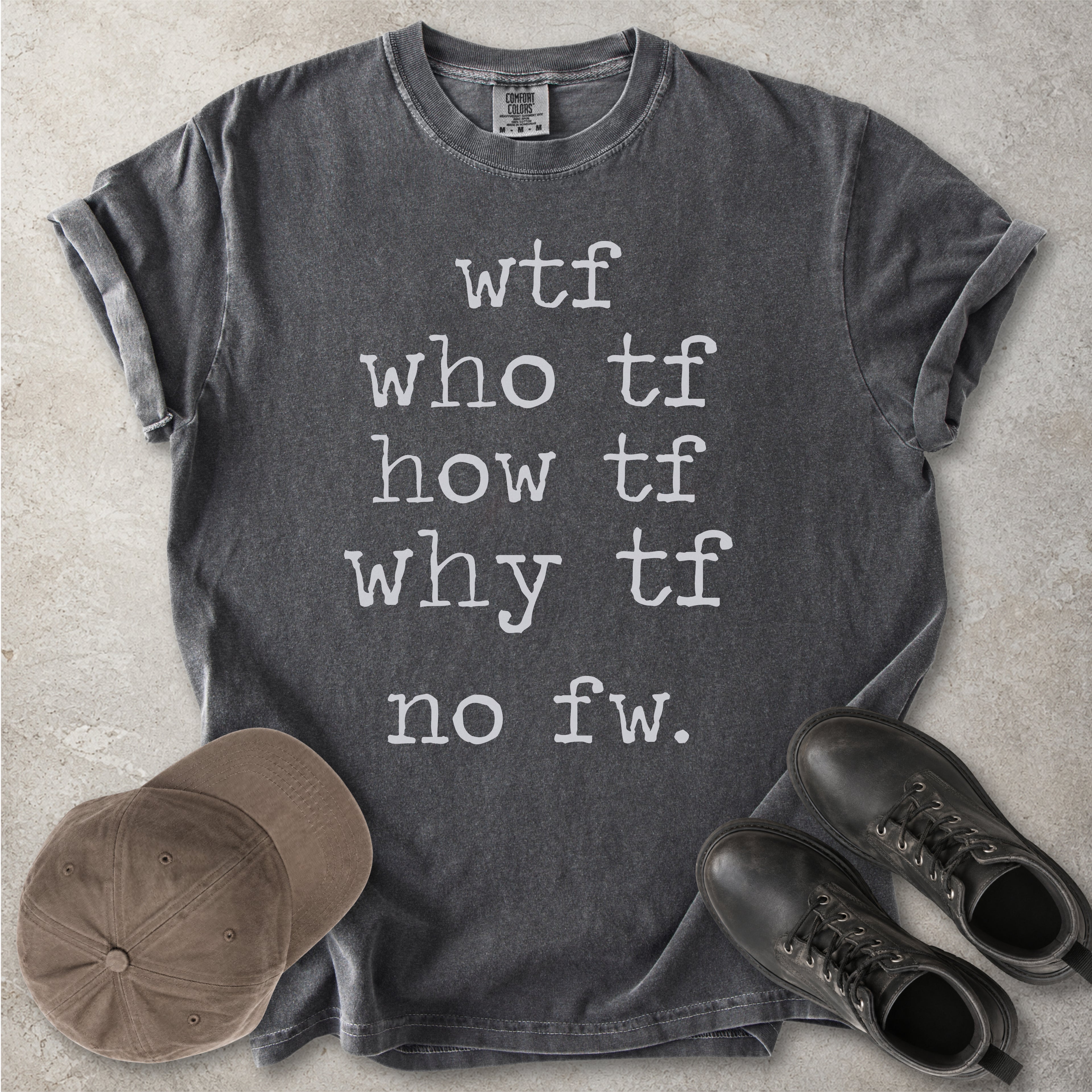 Grey Comfort Colors graphic T-shirt with grey text reading wtf, who tf, how tf, why tf and no fw, styled with a brown cap and black boots