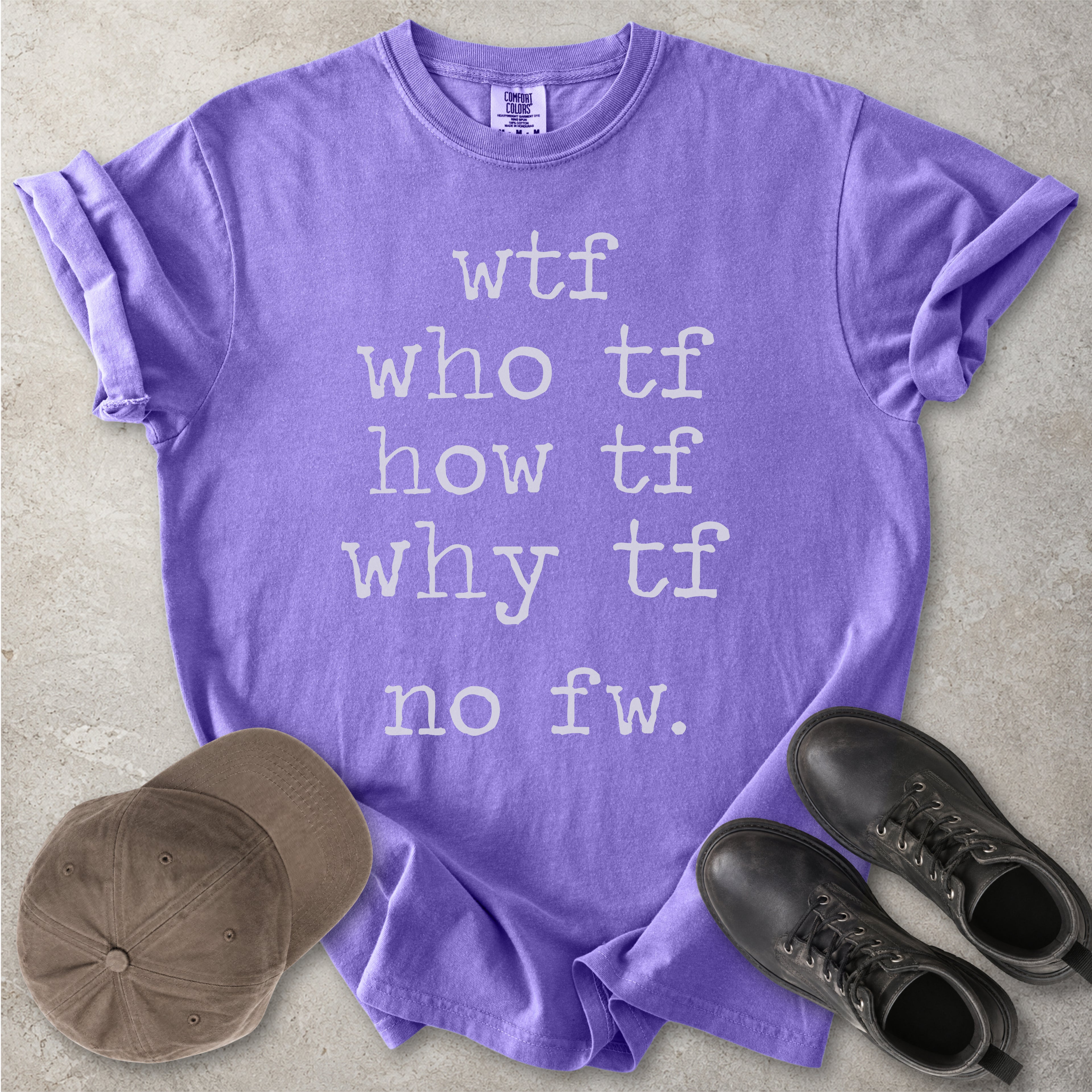 Purple Comfort Colors graphic T-shirt with grey text reading wtf, who tf, how tf, why tf and no fw, styled with a brown cap and black boots